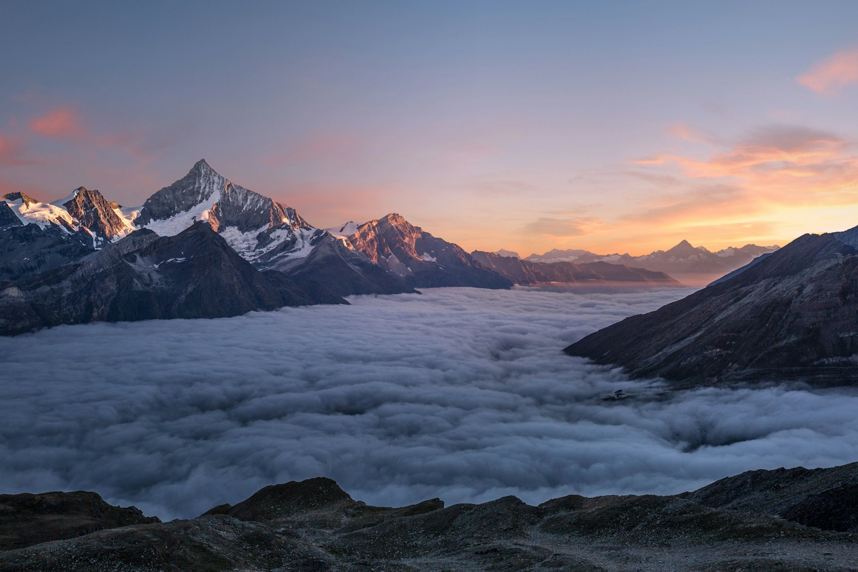 Un sommet émergeant au-dessus d'une mer de nuages, à l'aube.