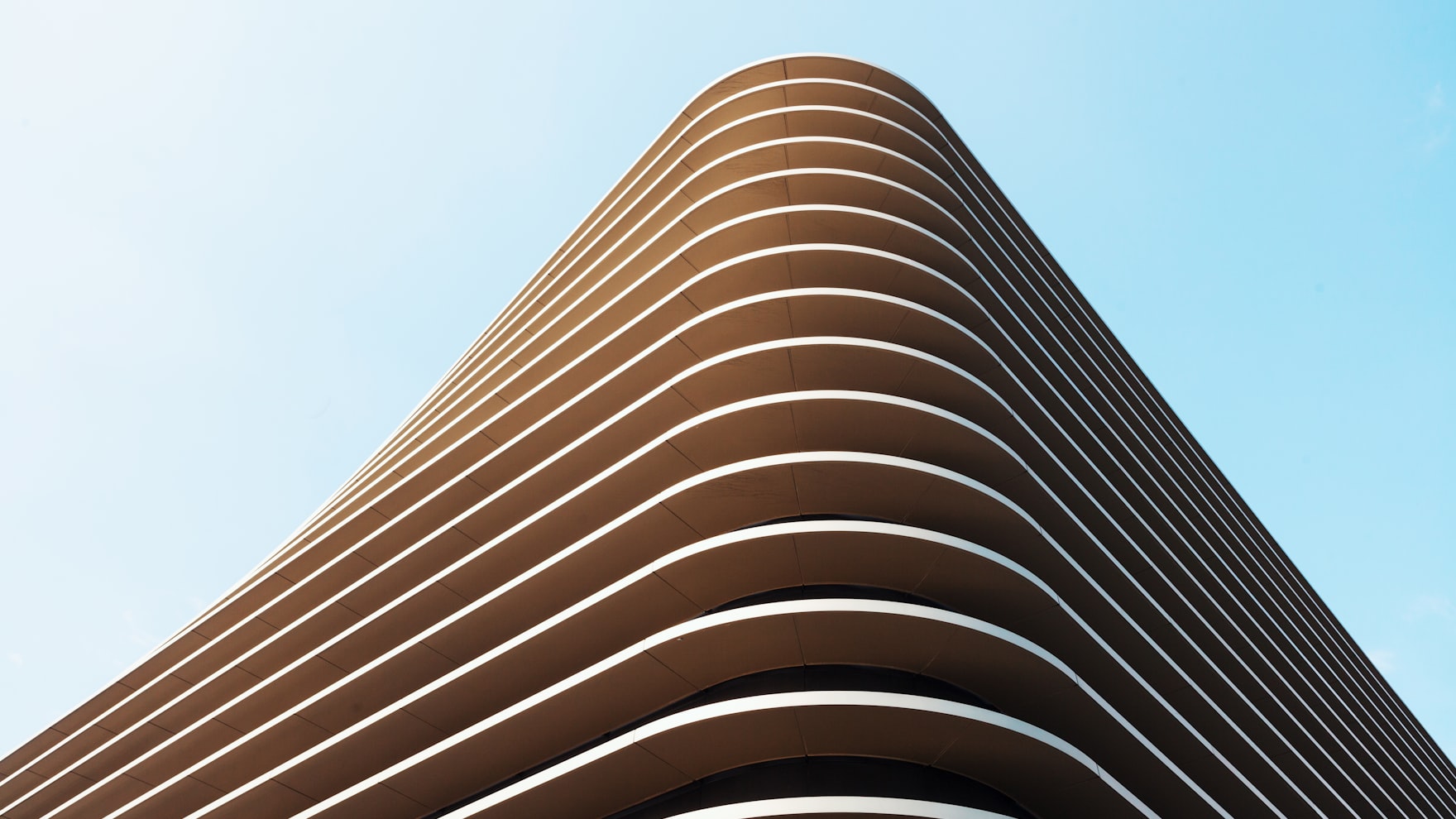 La façade d’un bâtiment aux lignes horizontales régulières épousant une courbe maîtrisée.